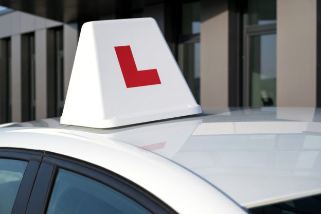 White car with a red 'L' learner sign on the roof